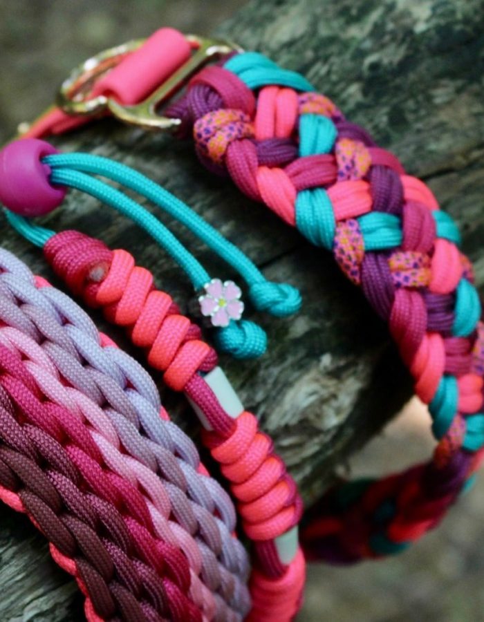 Un ensemble de colliers colorés est exposé sur une bûche, présentant une variété de motifs vibrants. Ces accessoires de mode pour chiens mettent en valeur divers nœuds et cordes, renforçant ainsi leur attrait extérieur.