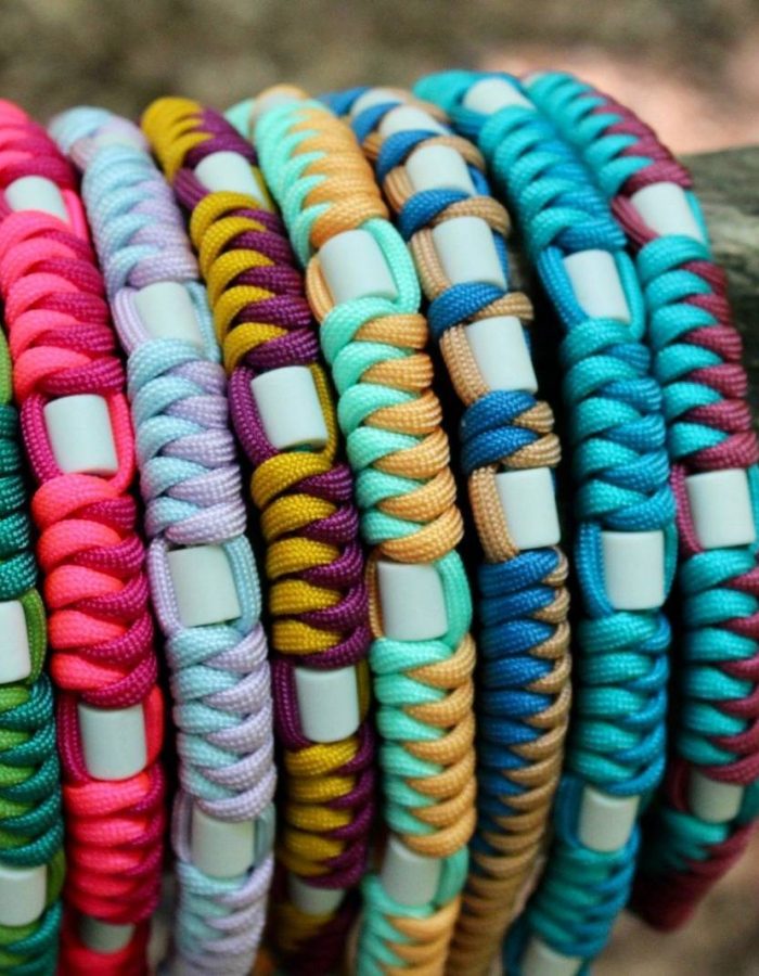 L'image présente une collection de colliers pour chiens colorés disposés sur une branche. Ces accessoires de mode signés Cody Création créent une esthétique extérieure dynamique. La composition met en valeur la variété et la beauté de chaque pièce.